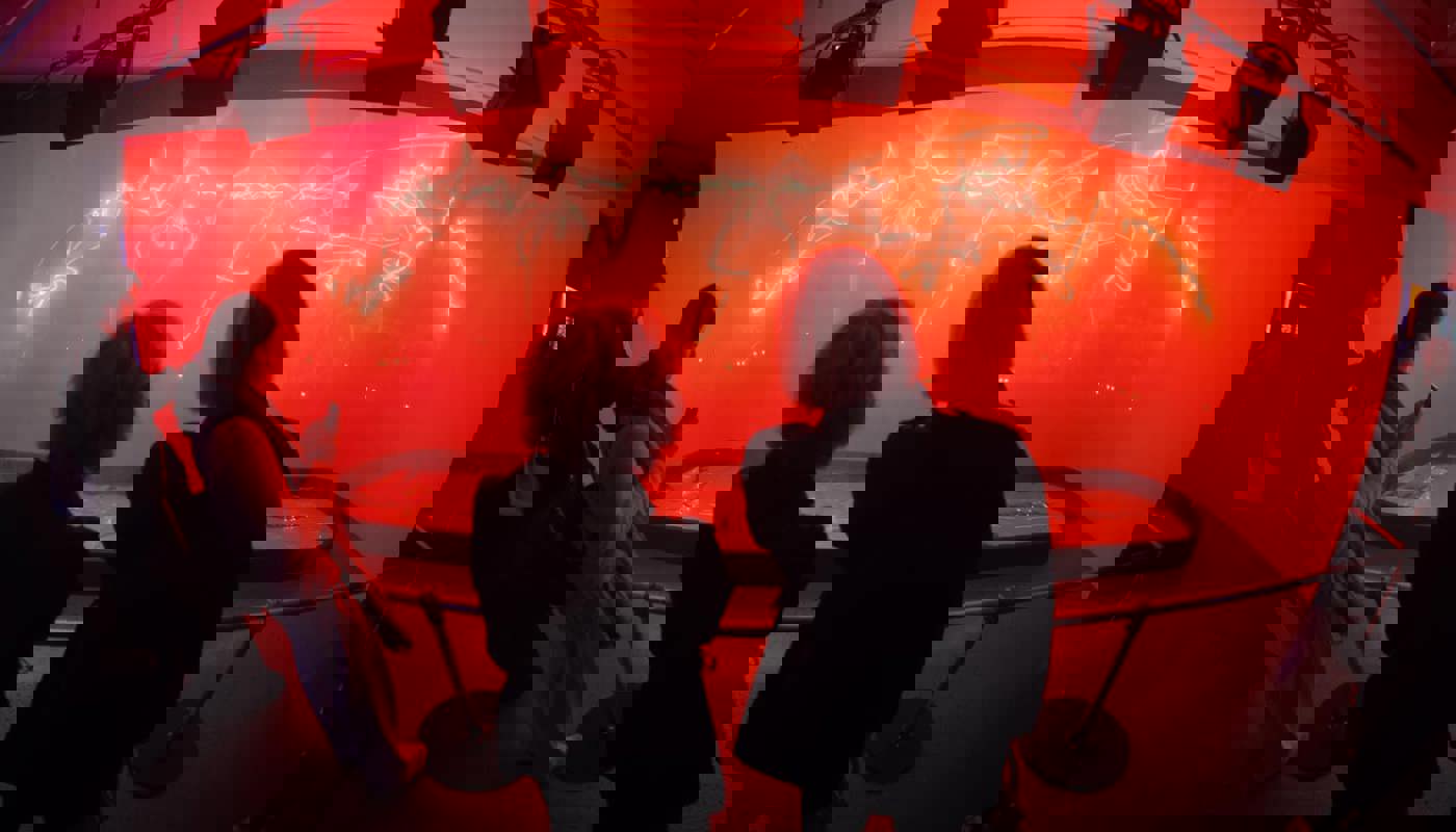 Behind shot of two people viewing orange lights.